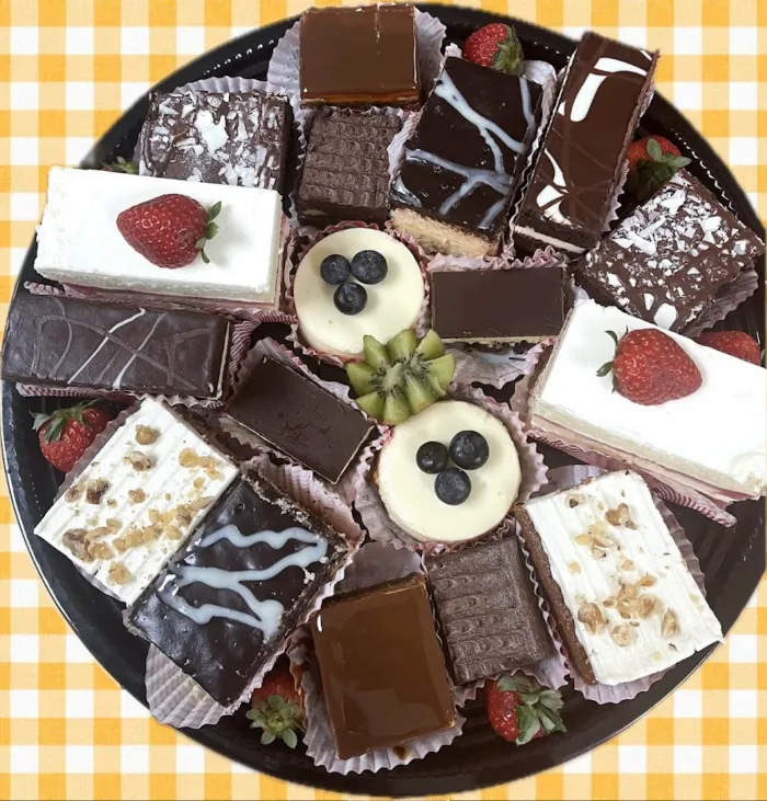 Assorted pastry platter with chocolate-glazed squares and fruit-topped mini cakes